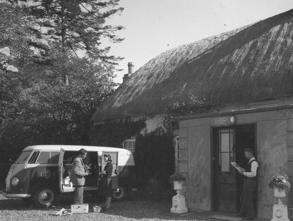 old van and people outside a thatched cottage