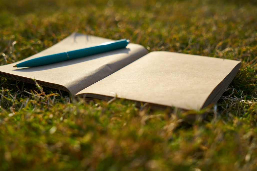 Open notebook and pen on grass
